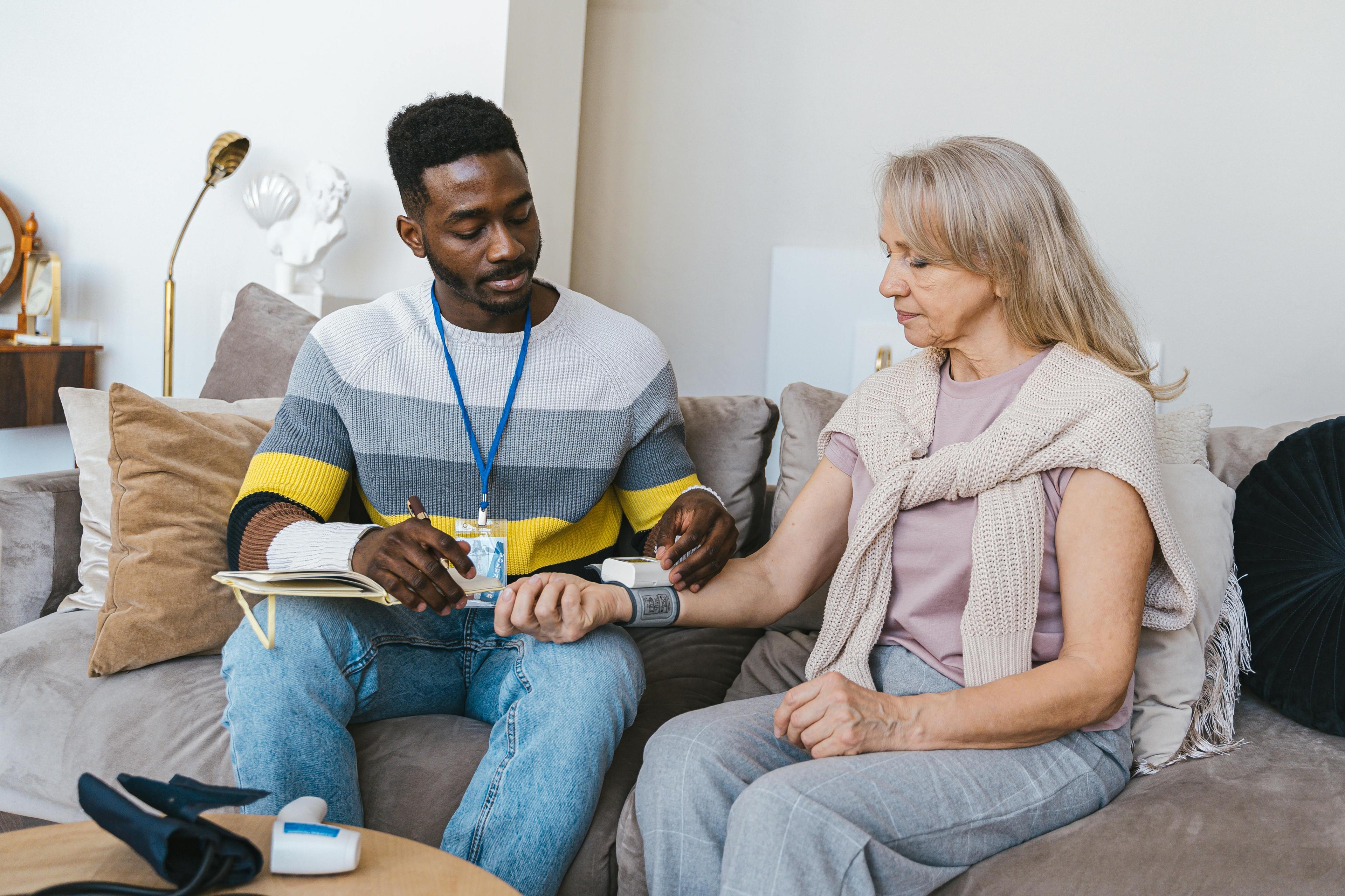 Carer supporting elderly person in home setting